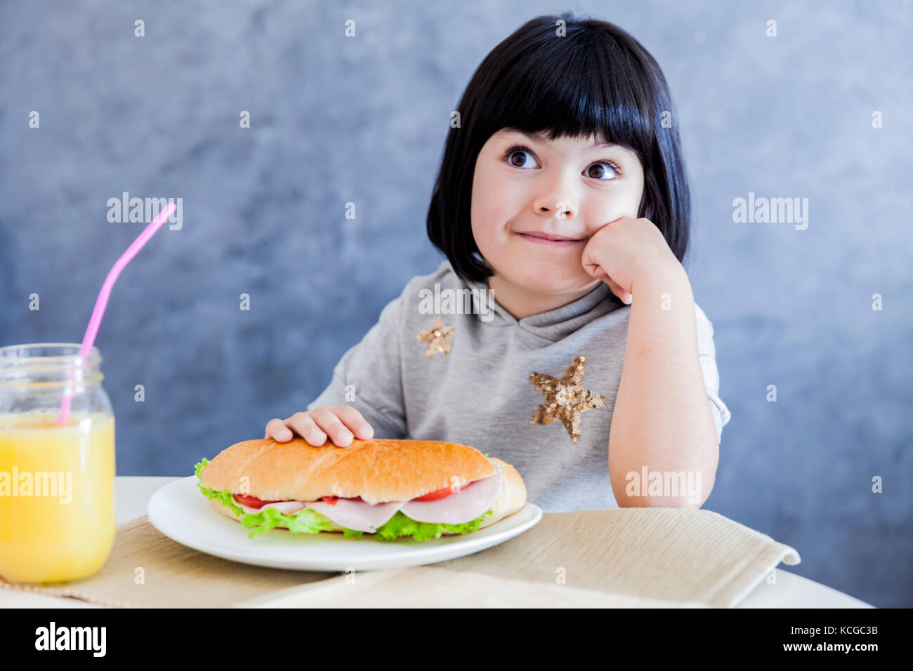 Carino capelli neri bambina sandwich di mangiare a casa Foto Stock