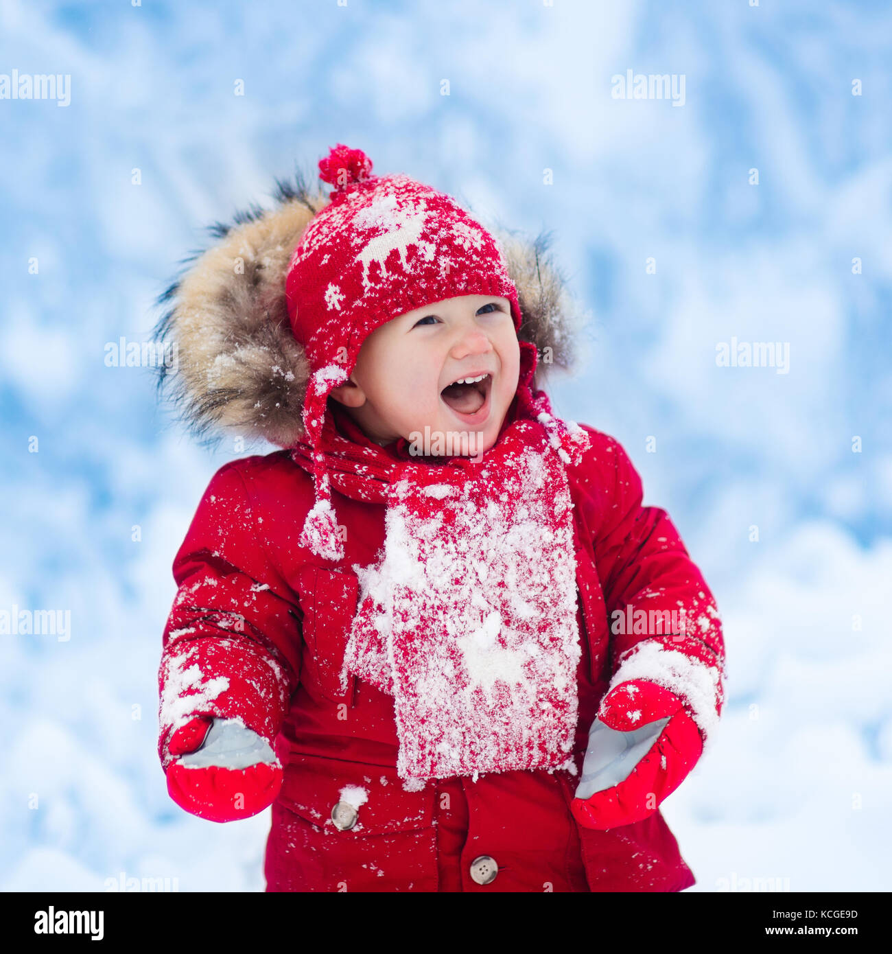 Il bambino gioca con la neve in inverno. piccolo bimbo ragazzo in giacca  rossa e il natale renne berretto lavorato a maglia la cattura di fiocchi di  neve in inverno parco sul