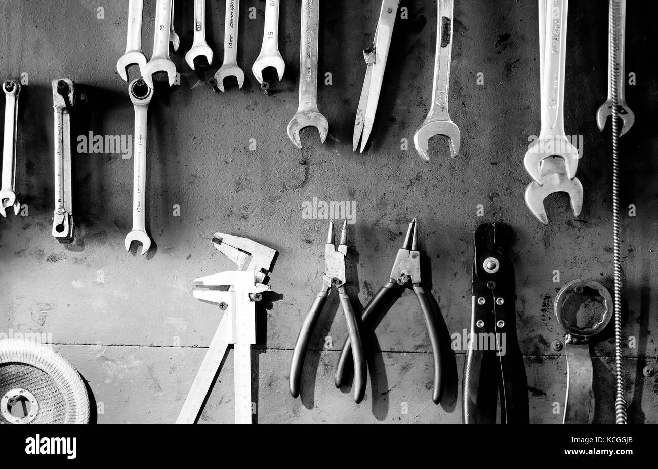Righe di meccanica strumenti di lavoro appendere un sudicio blu sullo sfondo di legno Foto Stock
