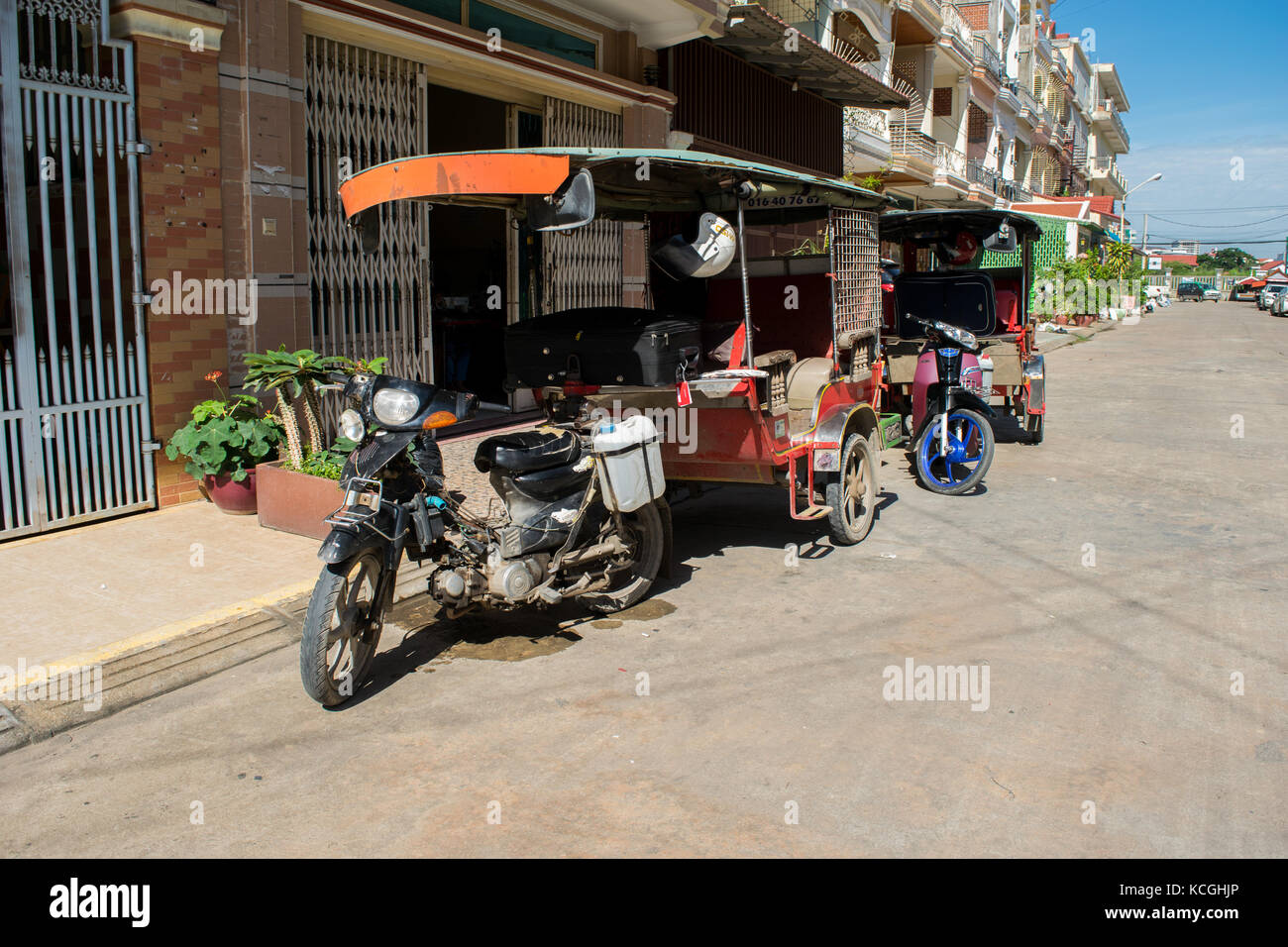 Due tuk-tuks, auto rickshaw, parcheggiato in una strada di Phnom Penh, in attesa per i clienti. Tuk-tuk sedi 5 passeggeri. Cambogia, Sud Est asiatico il trasporto Foto Stock