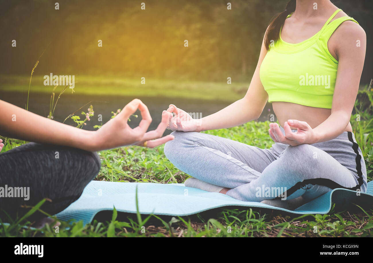 I giovani praticanti di yoga in gruppo facendo yoga sulla natura, uno stile di vita sano concetto. Foto Stock