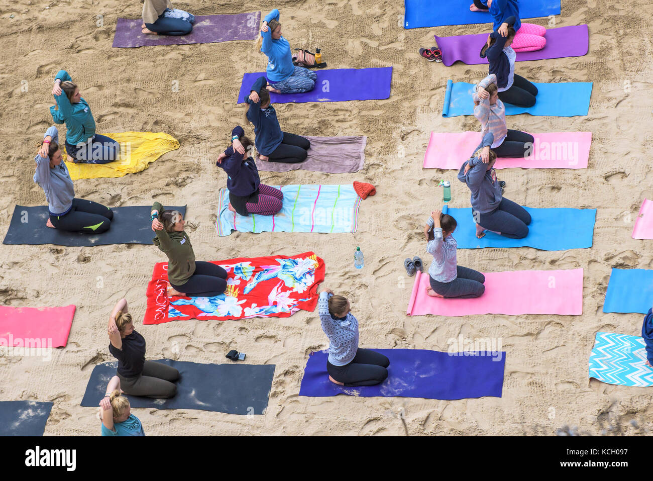 Lo Yoga su una spiaggia - le donne a praticare yoga su una spiaggia in Newquay, Cornwall Foto Stock