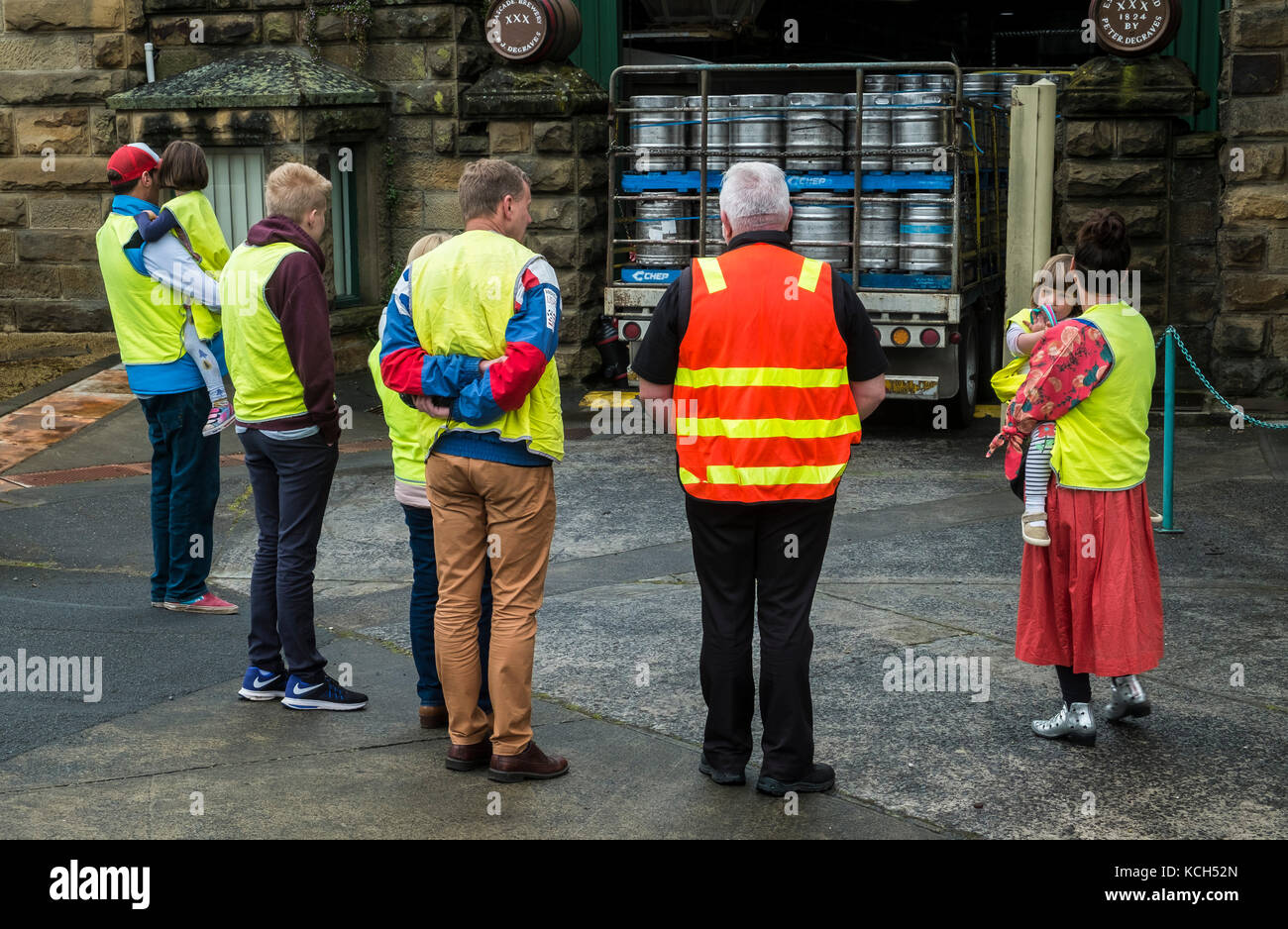 Una famiglia in alta visibilità giallo inizia un tour della fabbrica di birra a cascata nel sud di Hobart, Tasmania. La guida è in arancione hi vis vest. Foto Stock