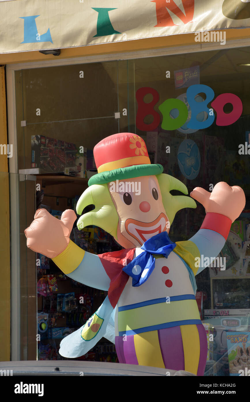 Un coloratissimo clown gonfiabile al di fuori di un negozio di giocattoli per bambini al dettaglio e la vendita di giochi e giocattoli per bambini. coco il clown vestito in maniera colorata Foto Stock
