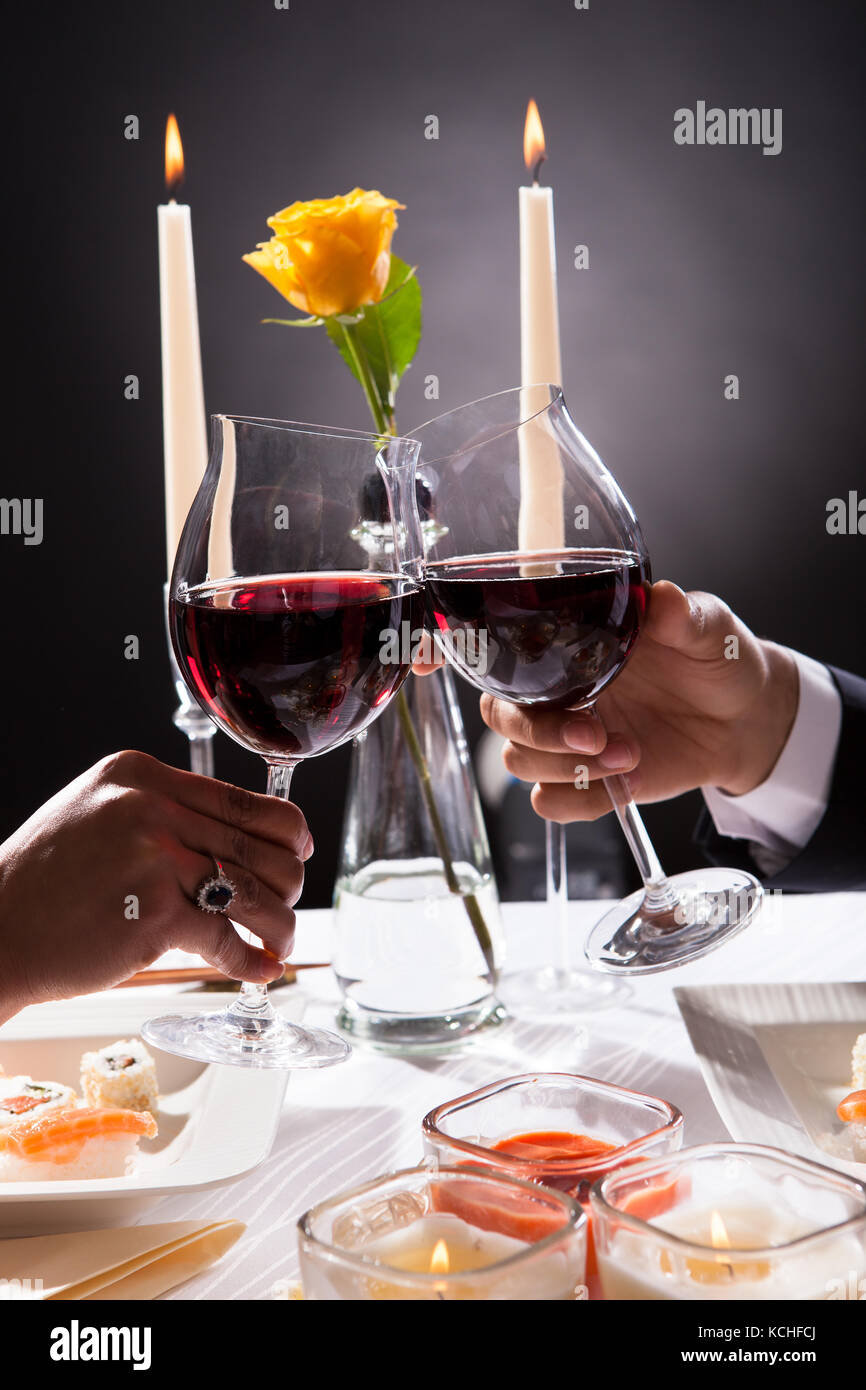 Chiudi - consente di accoppiare le mani di tostatura vino rosso su sfondo grigio Foto Stock