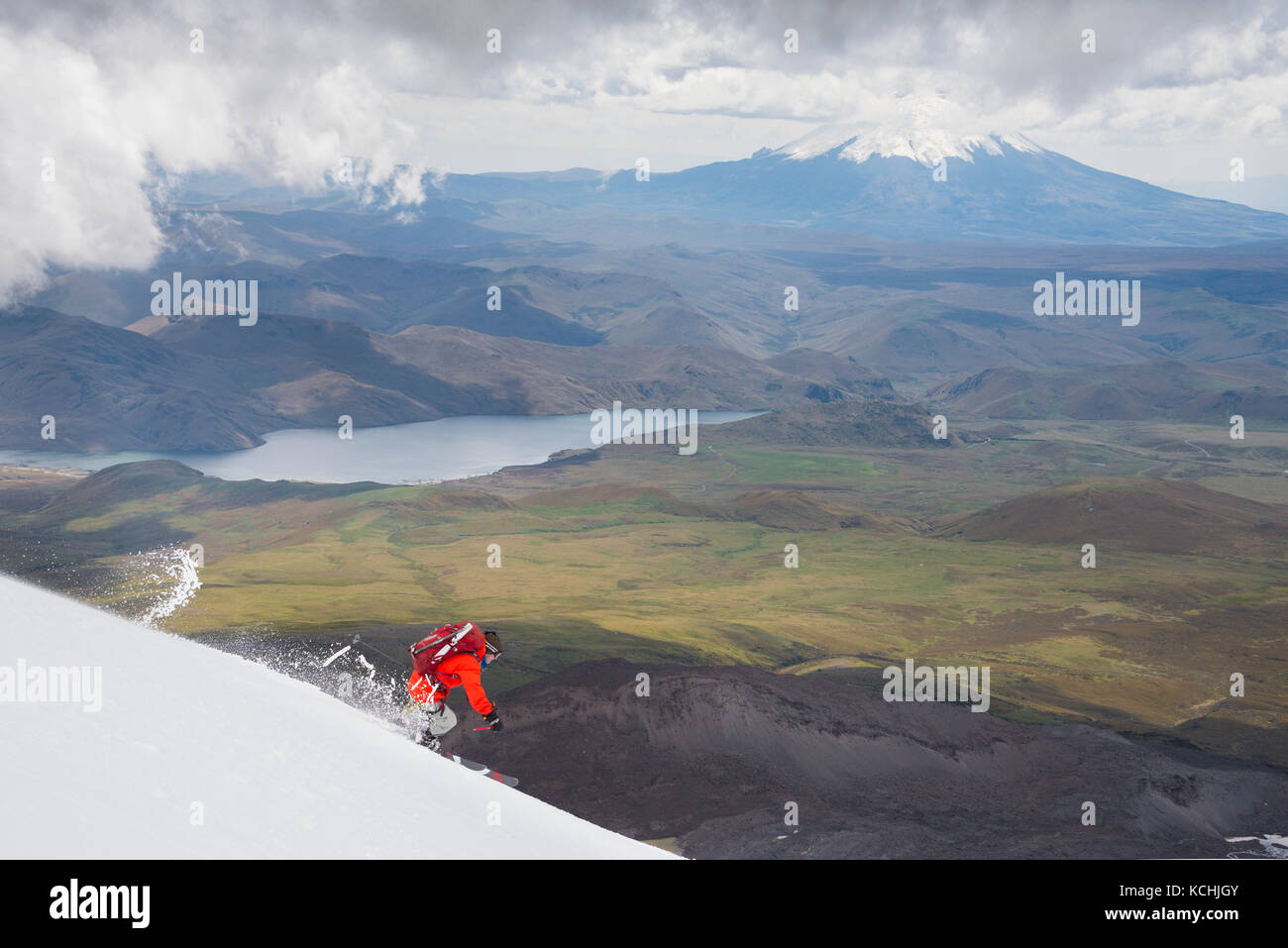 Un maschio di sciatore su una discesa di pendii di Volcan Antisana con dietro Cotopaxi, Ecuador Foto Stock