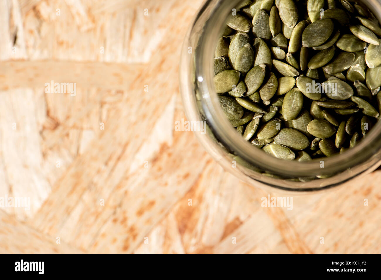 Mason vaso pieno di semi di zucca su una tavola di legno , sano cibo crudo Foto Stock