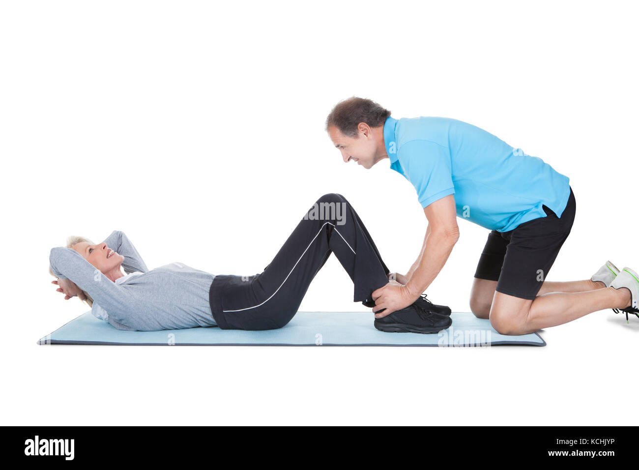 Donna matura facendo esercizio di fitness con l'aiuto dei trainer alla Palestra sportiva Foto Stock
