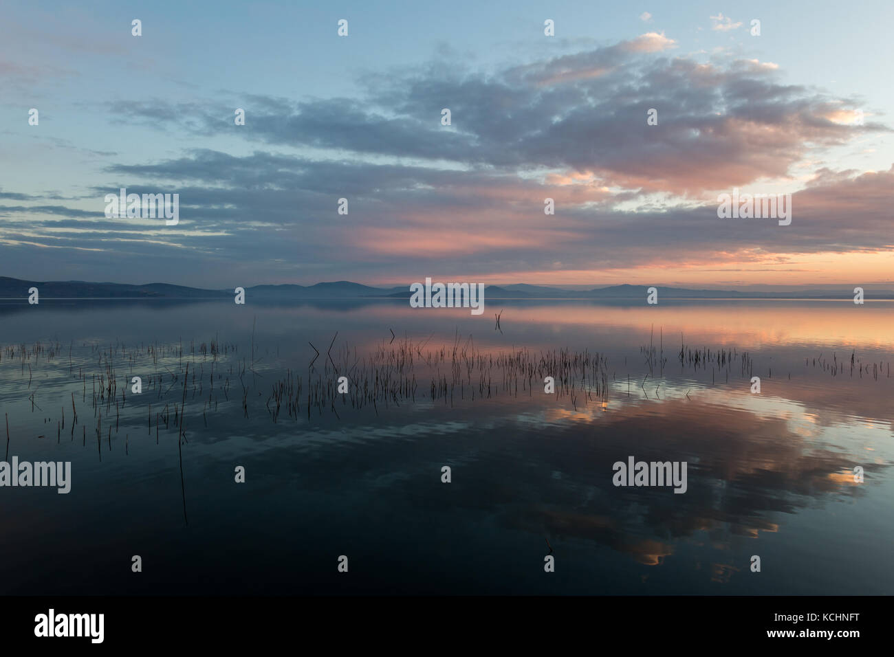 Perfetta e simmetrica nuvole riflessioni su un lago al tramonto, con caldi e toni morbidi Foto Stock