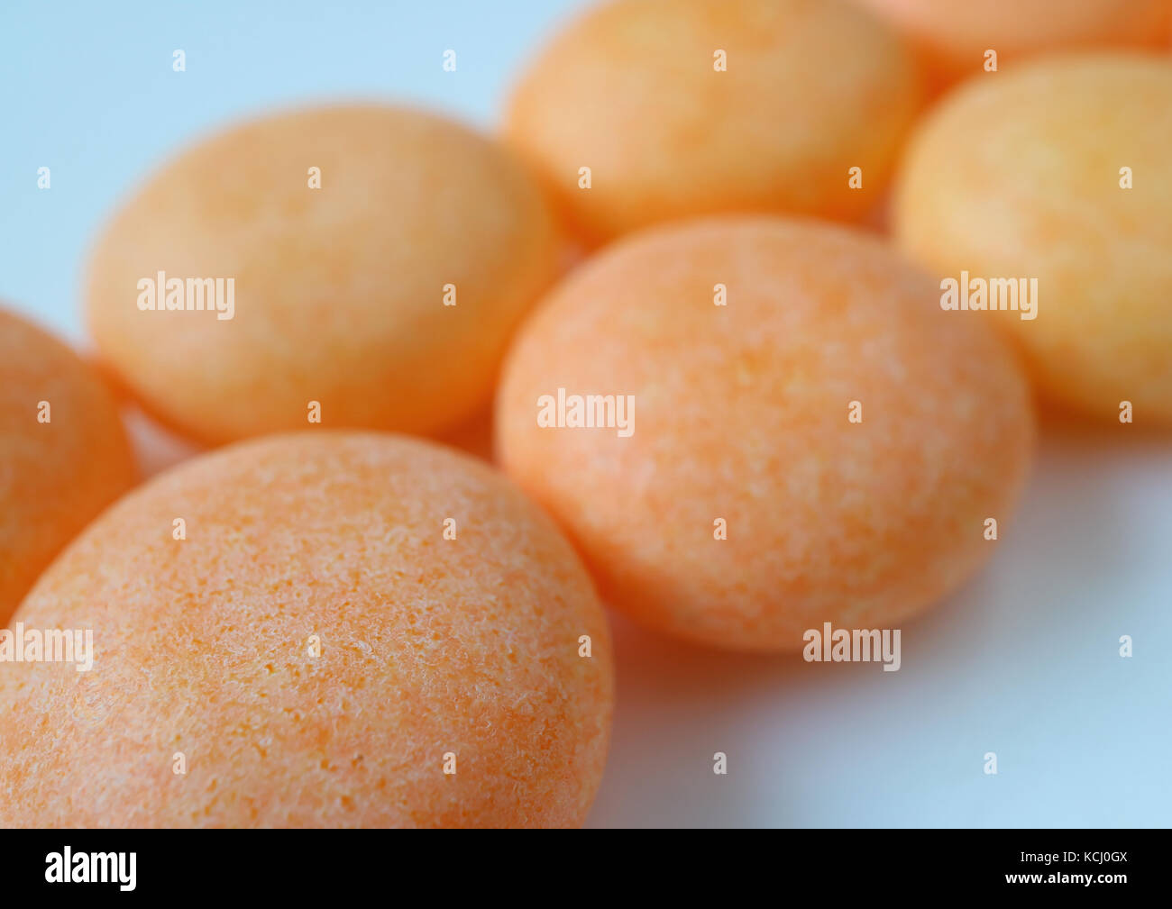 Schierate pastello colore arancione rivestite con zucchero caramelle rotonde, macro shot per texture e lo sfondo con il fuoco selettivo Foto Stock