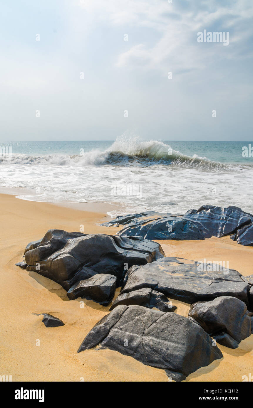 Onde crashin sulla bella spiaggia con grandi rocce nere, robertsport, Liberia, Africa occidentale Foto Stock