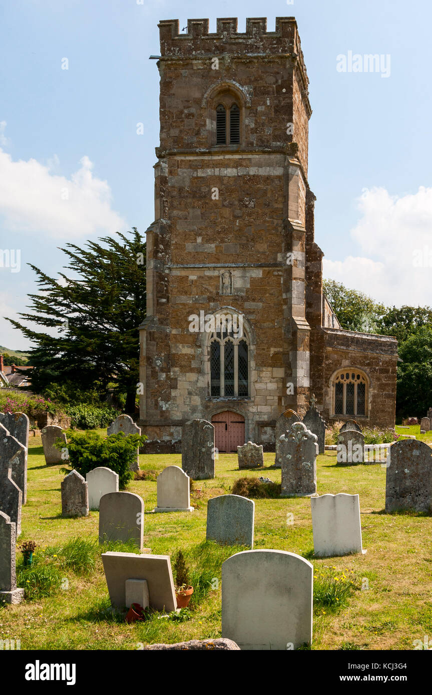 Il crenallated medievale torre della chiesa di St Nicholas metà nasconde un antico albero di Yew come ovelooks sagrato bagnata dalla metà giornata sole estivo Foto Stock