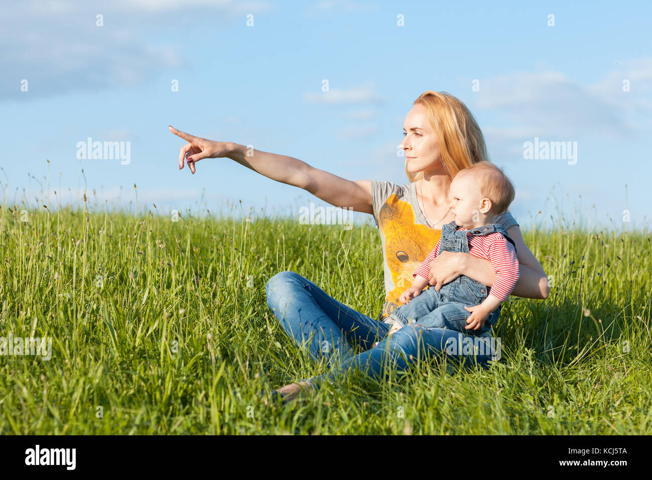 Ritratto di Madre e figlia nell'erba. mom punti in avanti a mano Foto Stock