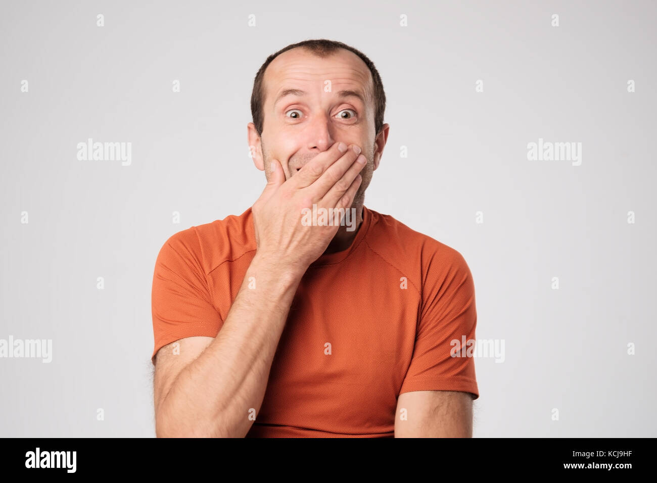 Coppia uomo caucasico in t-shirt la chiusura di una bocca con le mani su uno sfondo luminoso. Foto Stock