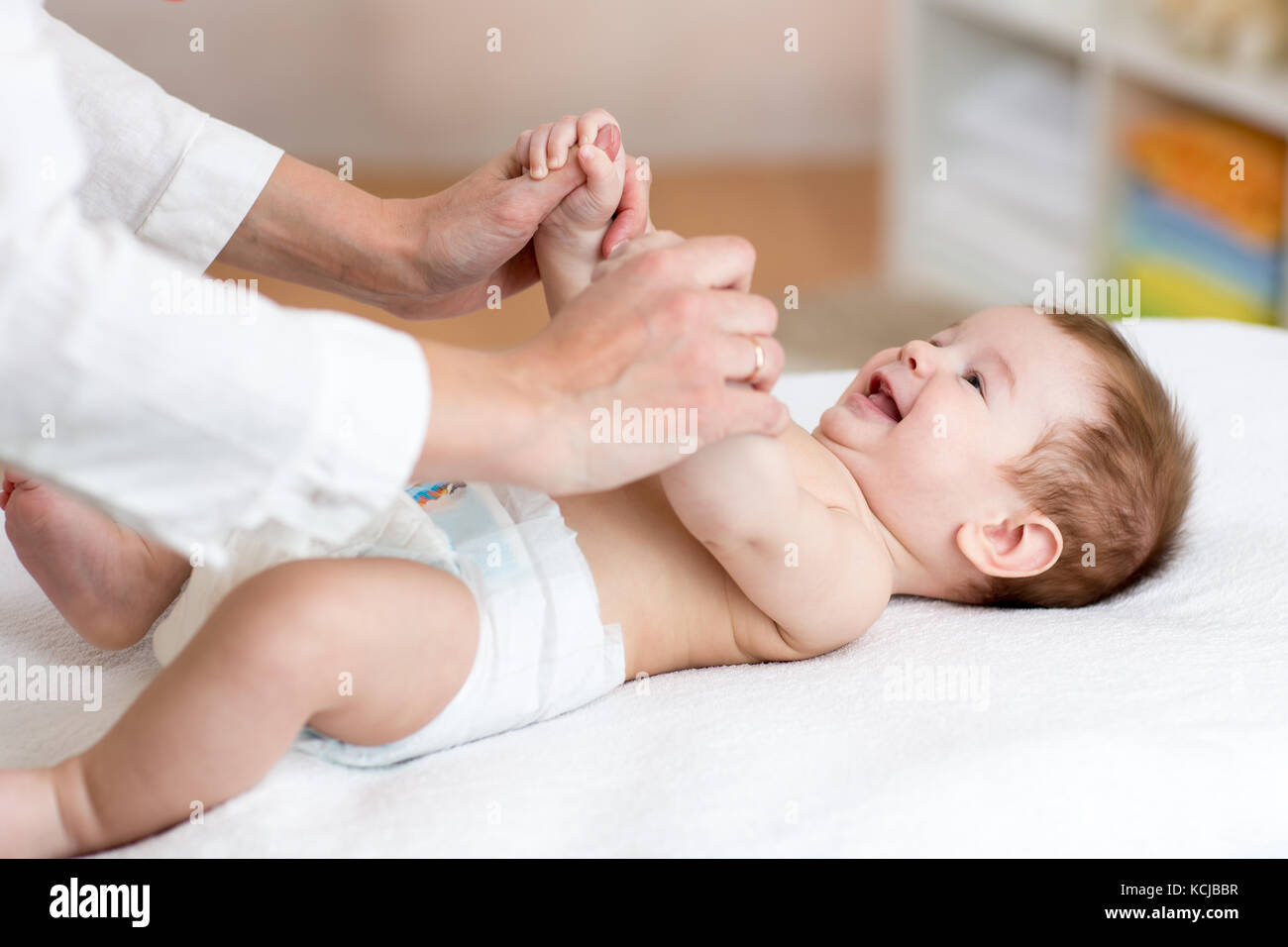 Baby massaggio. massagist massaggianti e fare ginnastica per bambino Foto Stock