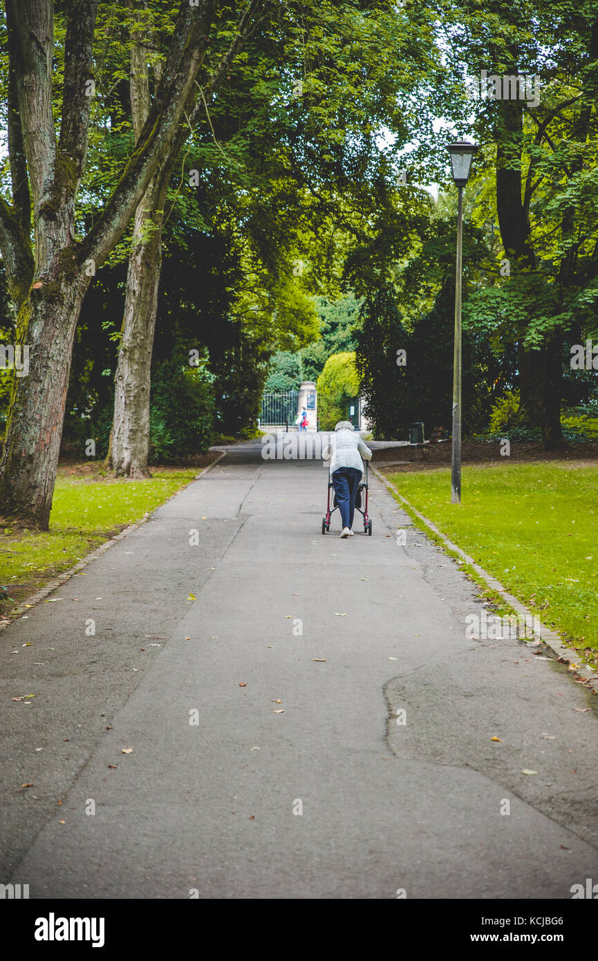 Una vecchia donna camminare da solo Foto Stock