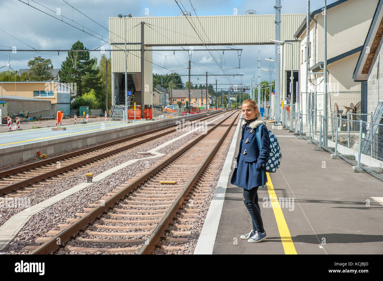 Ragazza bionda sta in piedi in una stazione di gare di steinfort e in attesa per il suo treno, Lussemburgo Foto Stock