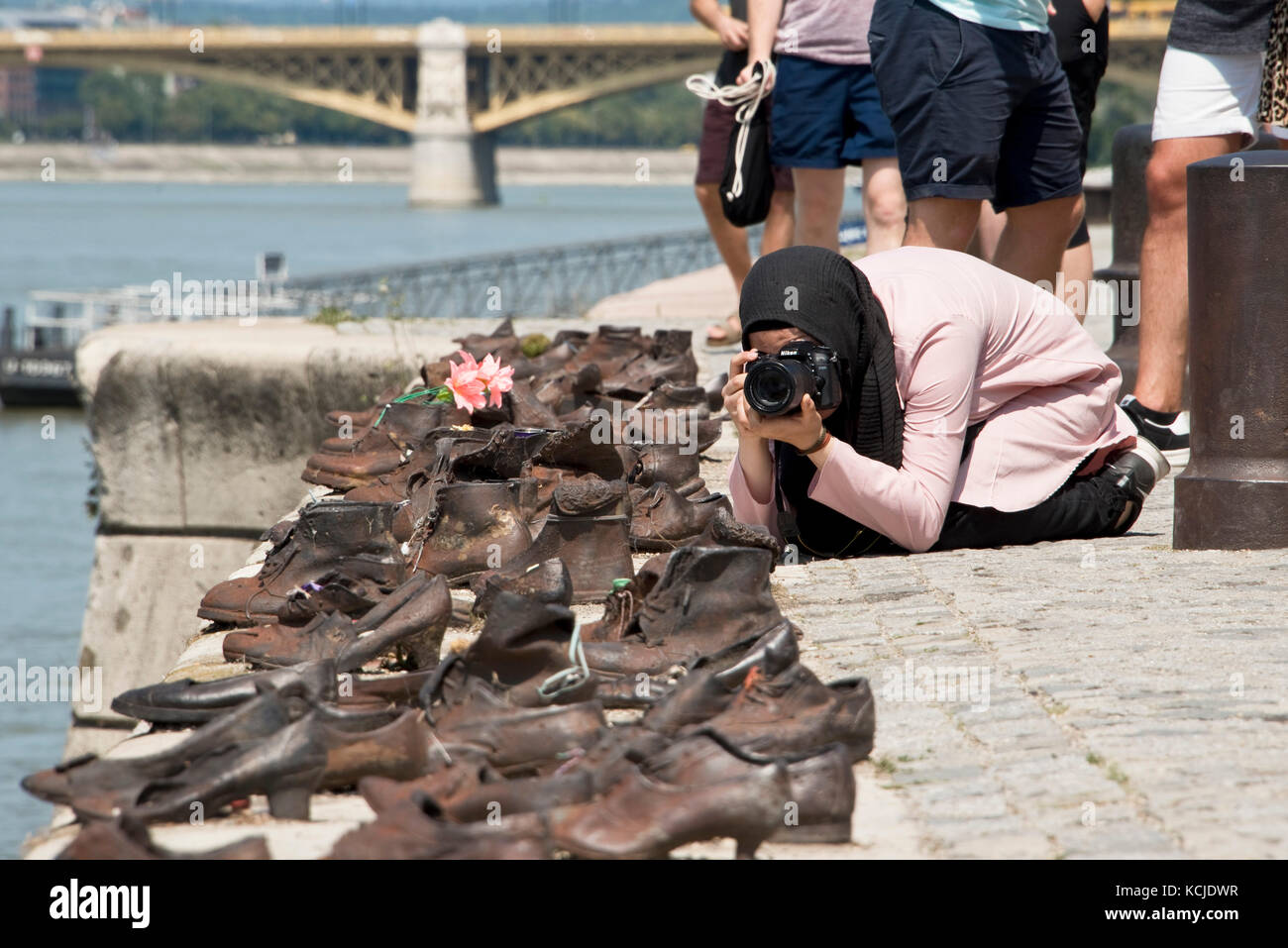 Le scarpe sulla sponda del Danubio memorial a Budapest in una giornata di sole con un turista a scattare foto. Foto Stock