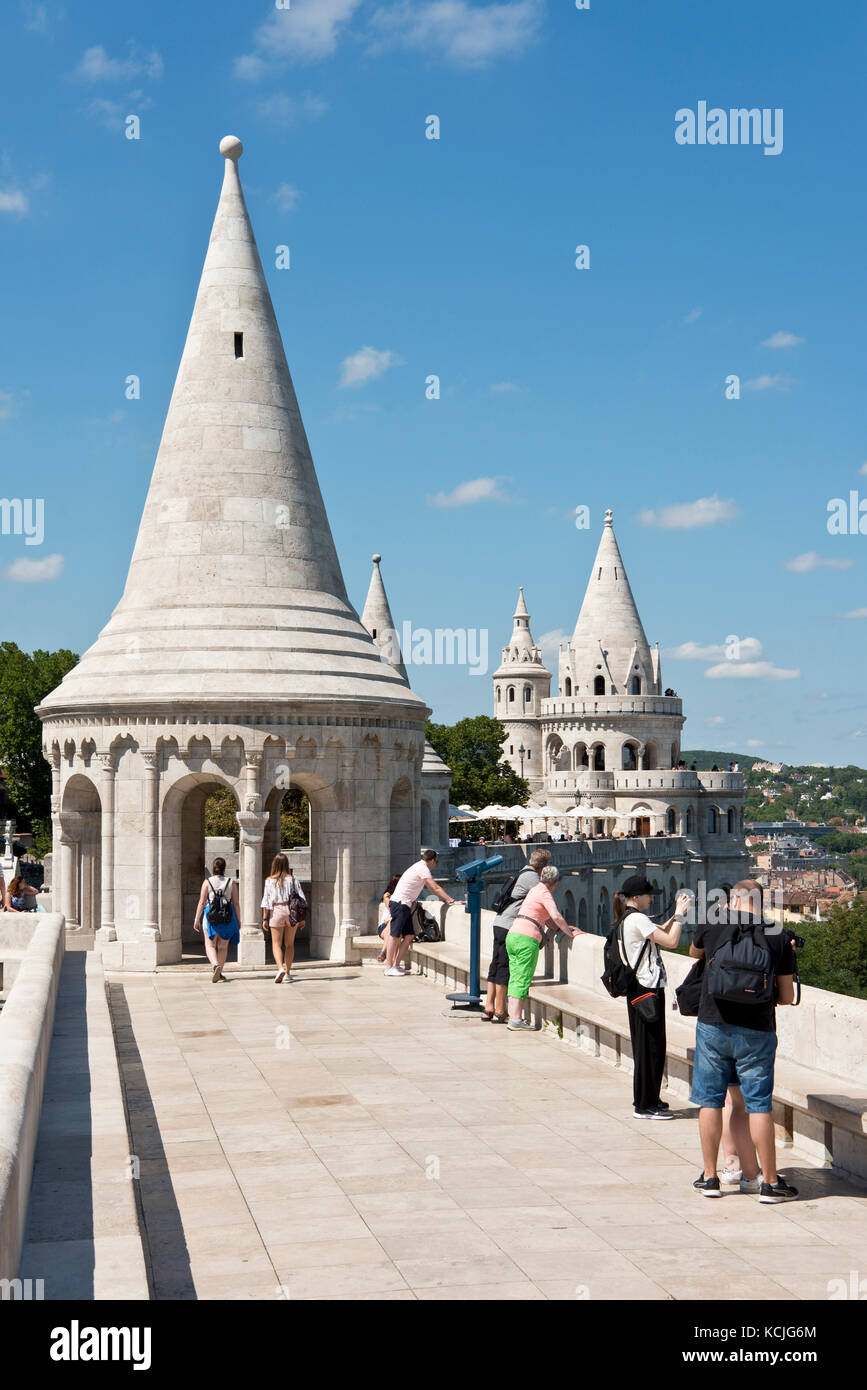 Turisti sulle pareti del Bastione dei pescatori di Budapest guardando la vista e scattando foto in una giornata soleggiata con il cielo blu. Foto Stock
