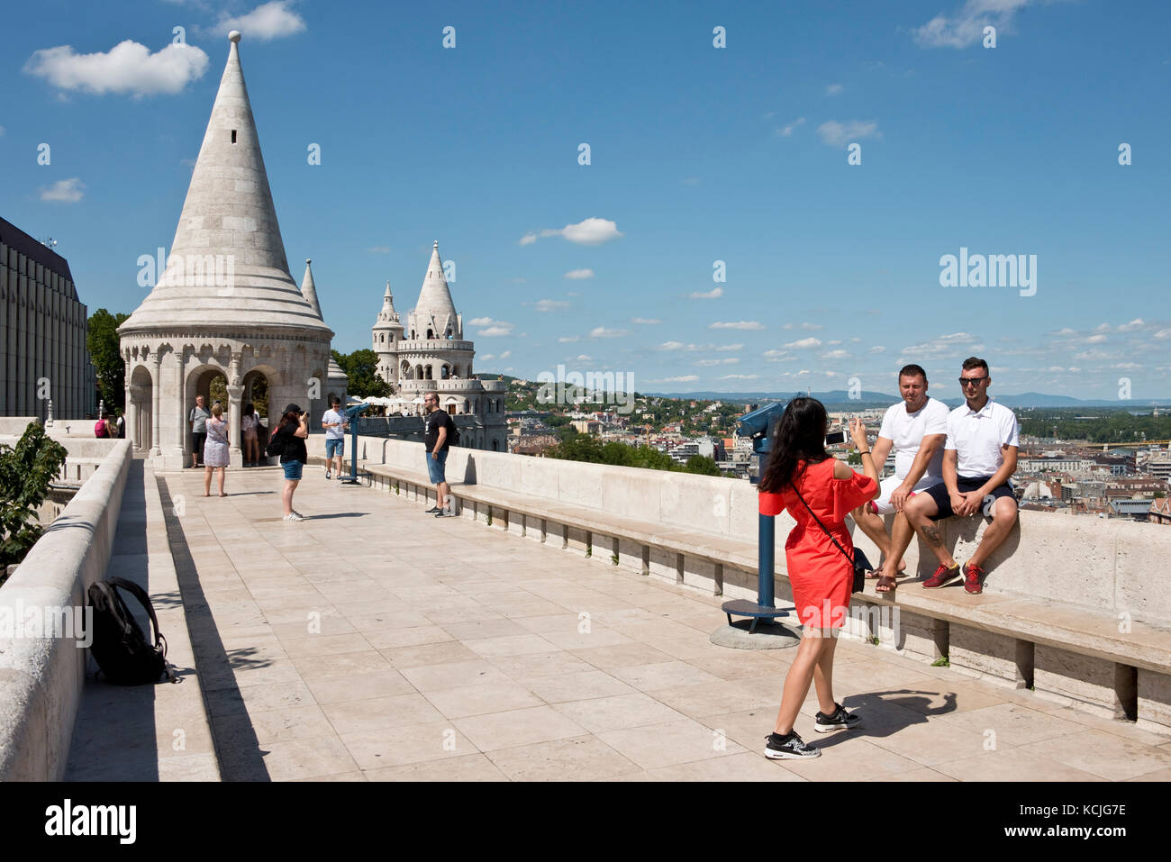 Turisti sulle pareti del Bastione dei pescatori di Budapest guardando la vista e scattando foto in una giornata soleggiata con il cielo blu. Foto Stock