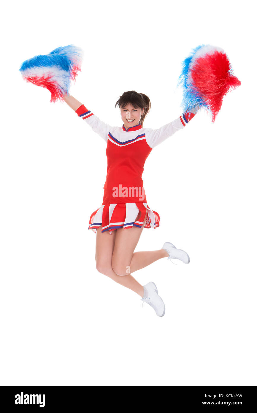 Felice cheerleader jumping con il pom-pom su sfondo bianco Foto Stock