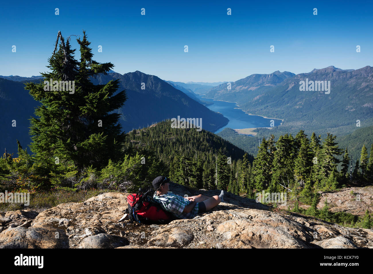Un escursionista solitario prende una pausa sul fiore sentiero di cresta che si affaccia sul lago buttle in strathcona park, strathcona park, centro di Isola di Vancouver, British Columbia, Canada Foto Stock
