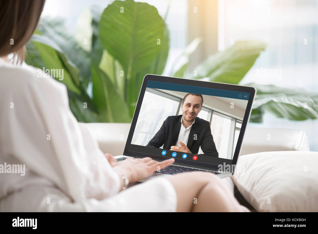 Giovane donna seduta sul divano comunica con l uomo in abito formale tramite chiamata video applicazione. giovane chat. lunga relazione di distanza, virtual comm Foto Stock