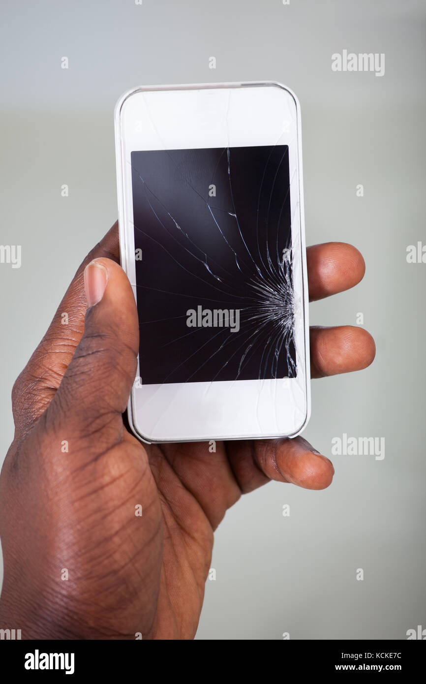 Close-up di un imprenditore la mano che regge il cellulare con schermo incrinato Foto Stock