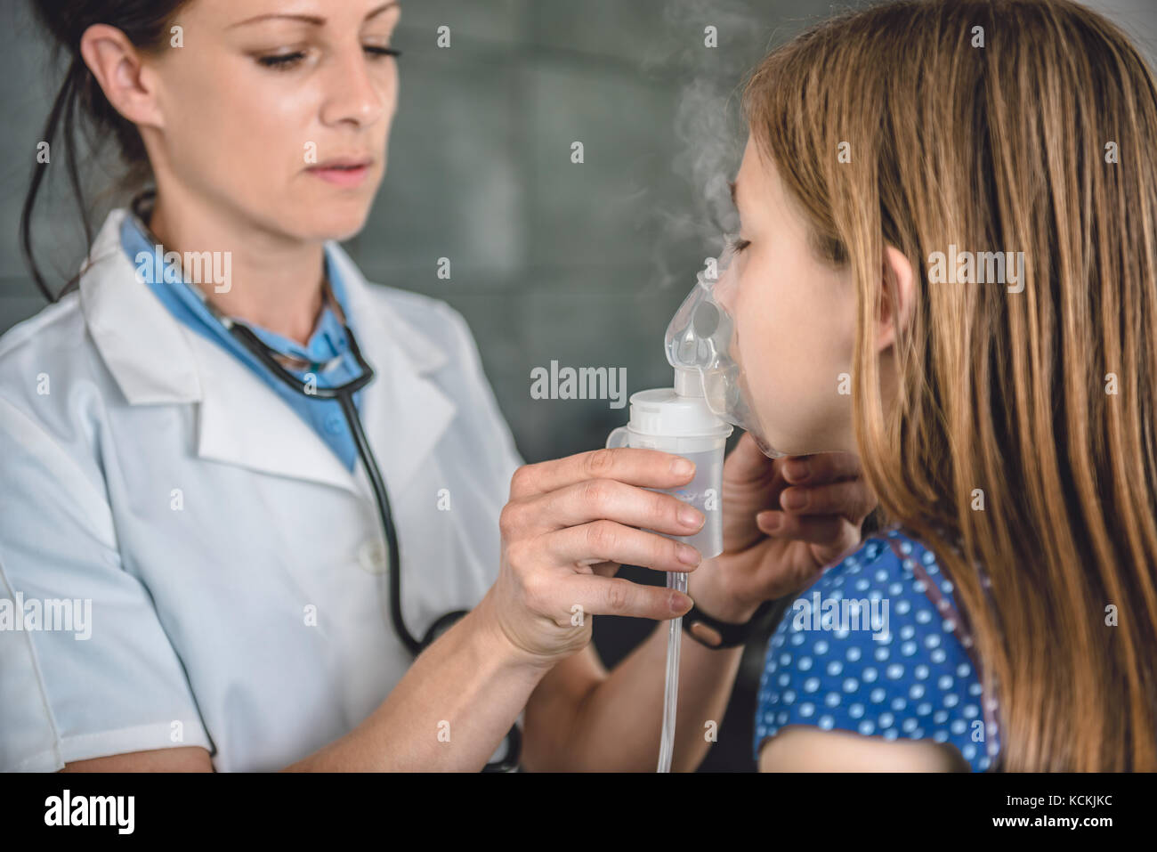Pediatria medico tenere una maschera inalatore di vapore a una bambina di respirazione attraverso un nebulizzatore a vapore Foto Stock