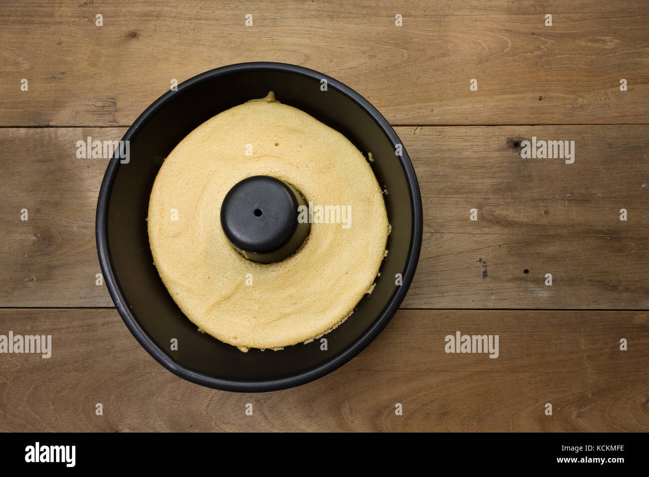 Torta di cotone al caffè in teglia rotonda nera, pronta a mangiare, su un rustico tavolo di legno, fatta in casa, piatto Foto Stock