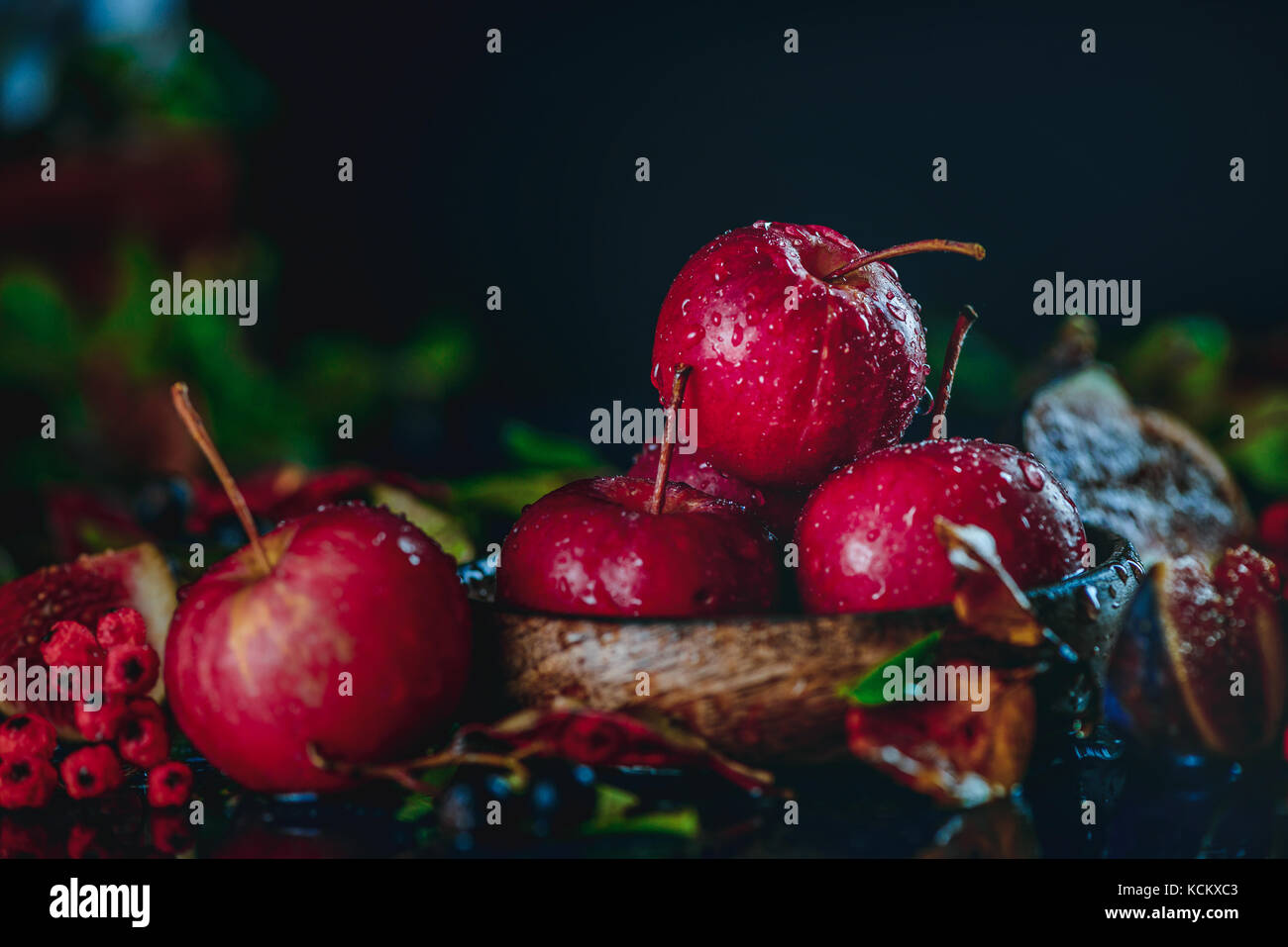 Rosso di mele in miniatura di close-up in un autunno ancora in vita con caduta foglie scure della fotografia di cibo con copia spazio. concetto di raccolto Foto Stock