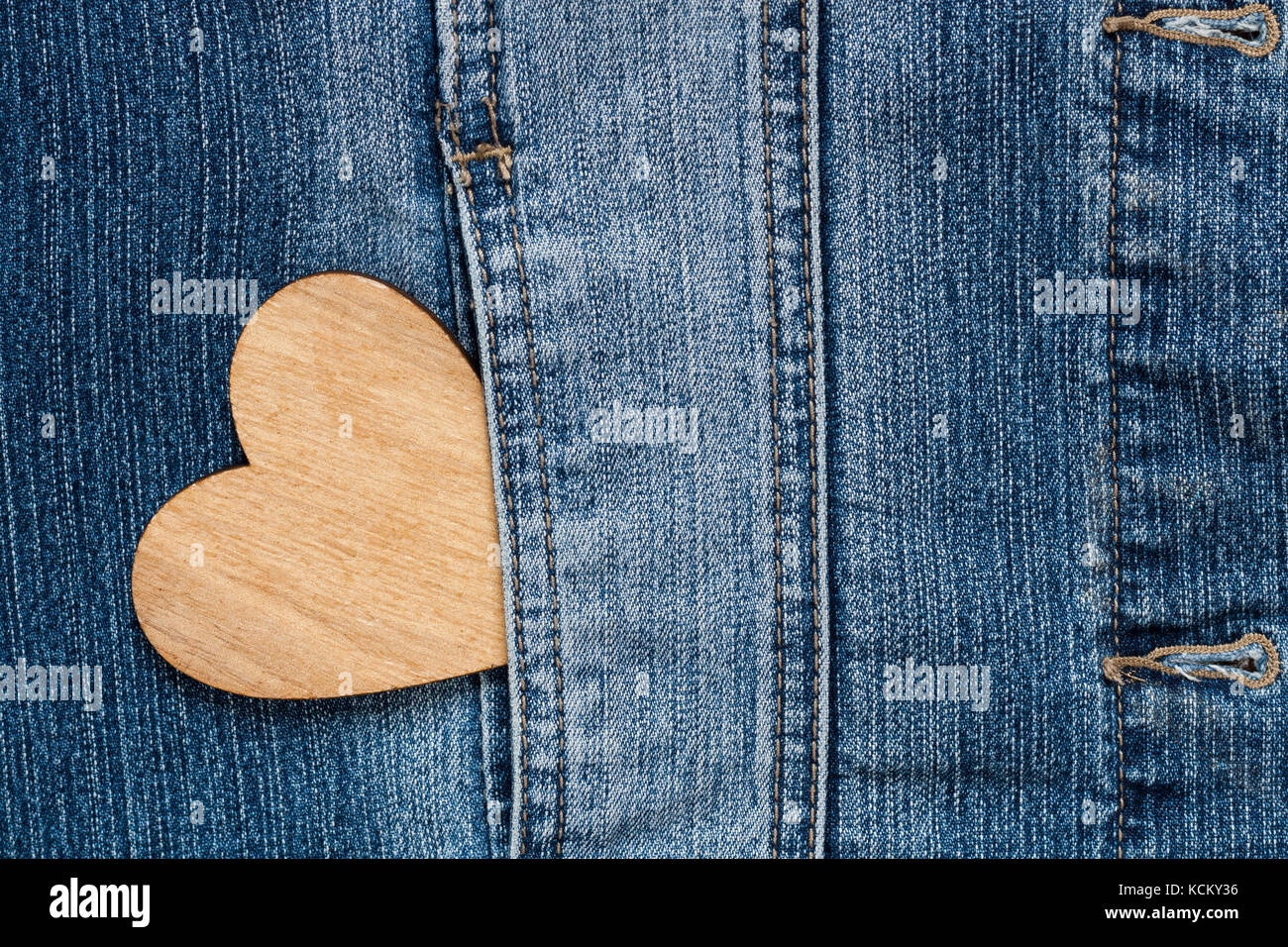 In legno marrone cuore nella tasca dei jeans blu della giacca Texture di sfondo Copyspace. Foto Stock