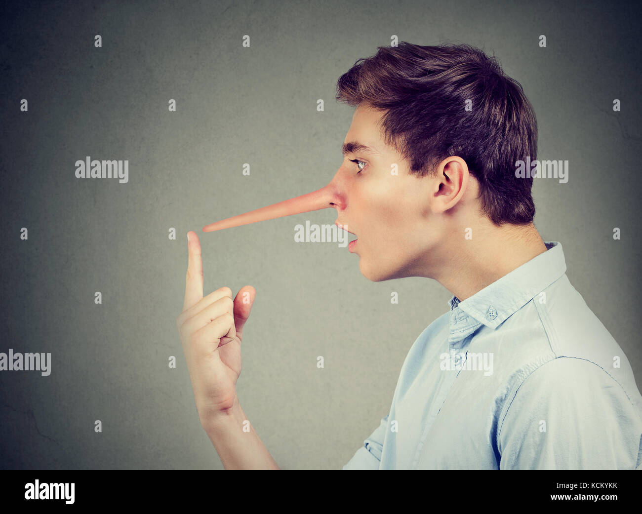 Uomo con il naso lungo isolato sul muro grigio Sfondo. bugiardo concetto. le emozioni umane, sentimenti. Foto Stock