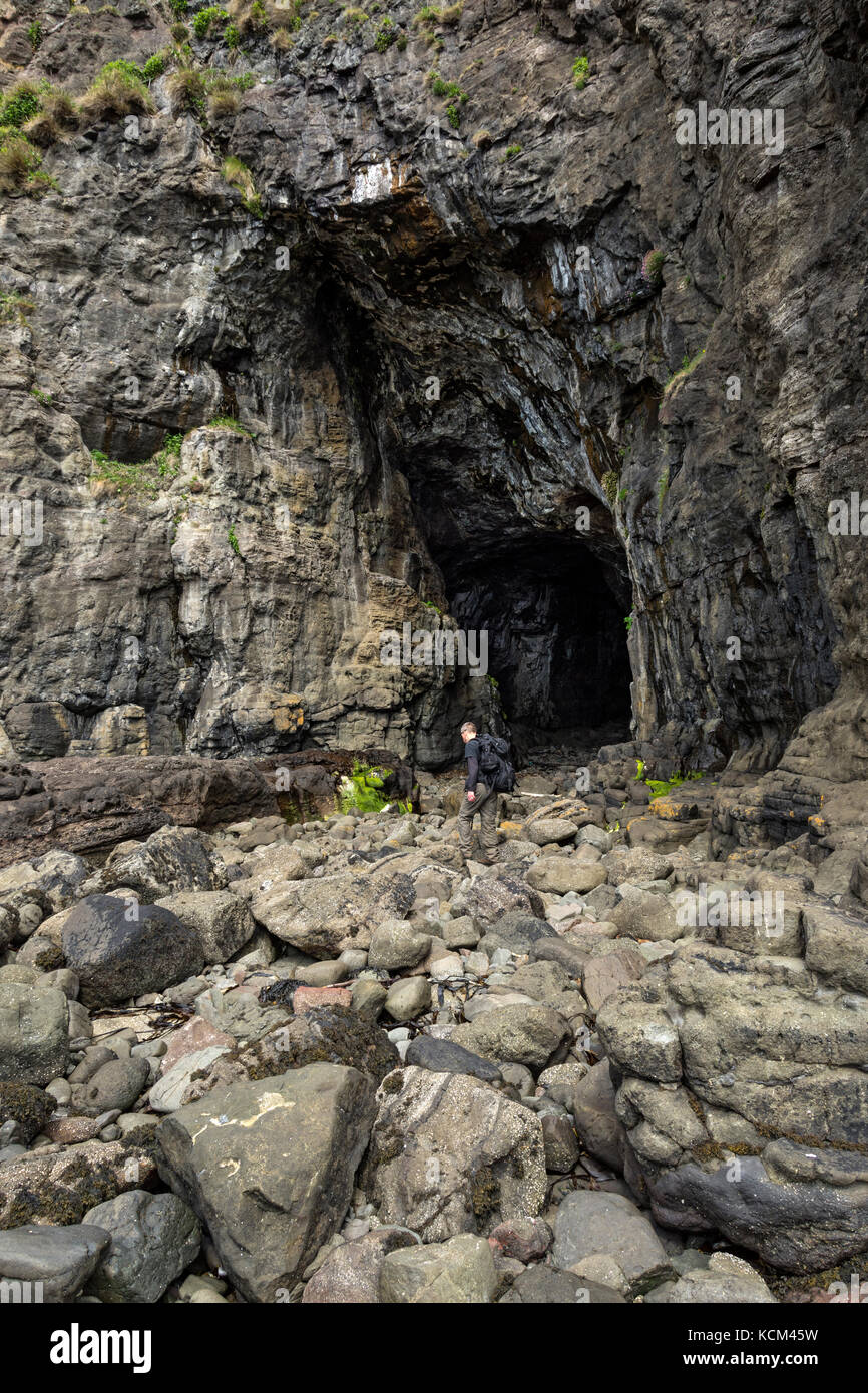 Un camminatore all'ingresso della Cathedral Cave, vicino a Galmisdale sull'Isola di Eigg, Scozia, Regno Unito Foto Stock
