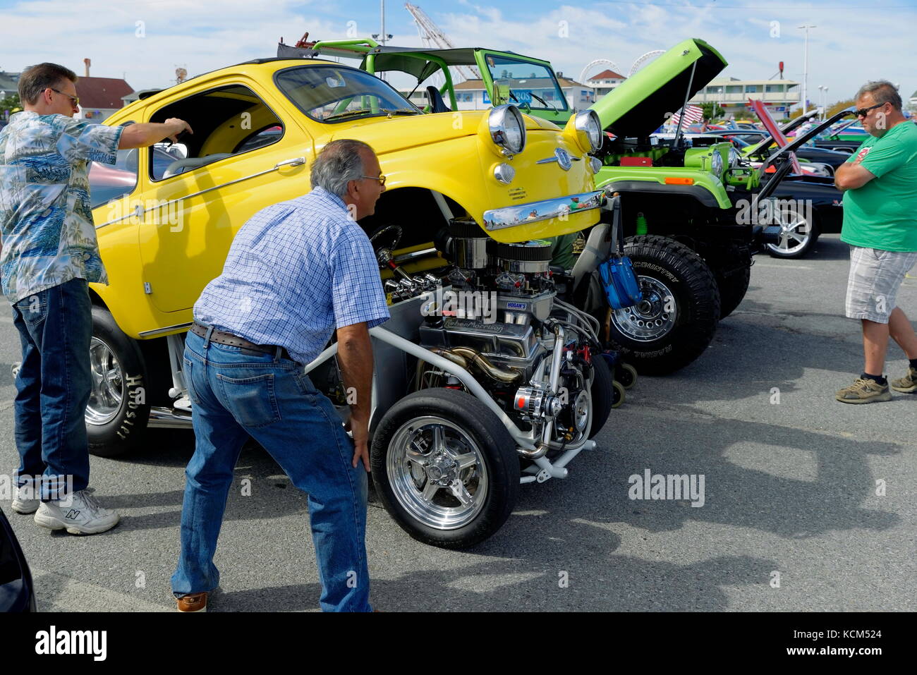 Tre uomini vedere una mini auto gialla asta calda al annuale Endless Summer Cruisin, Ocean City, Maryland, Stati Uniti. Foto Stock