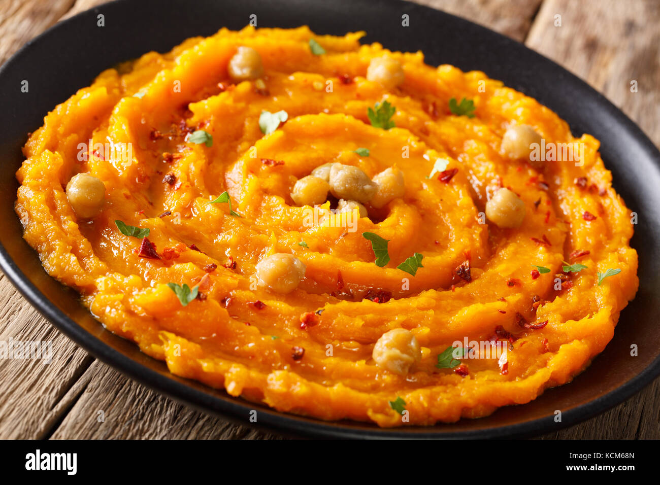 Organici di hummus con la zucca, pepe e le erbe aromatiche close-up su una piastra orizzontale. Foto Stock