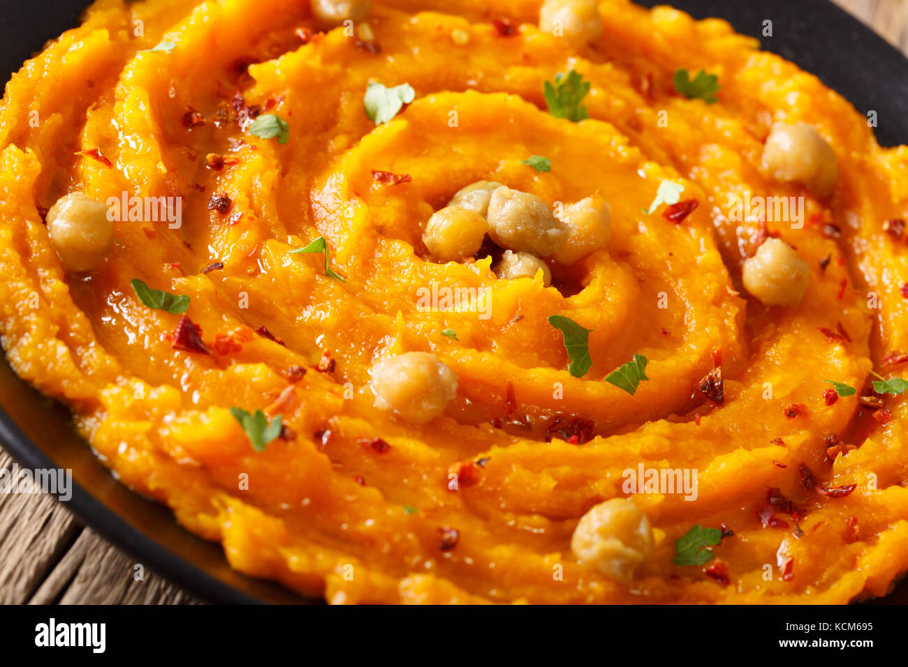 Alimento naturale: hummus con la zucca, pepe e verdi close-up su una piastra orizzontale. Foto Stock