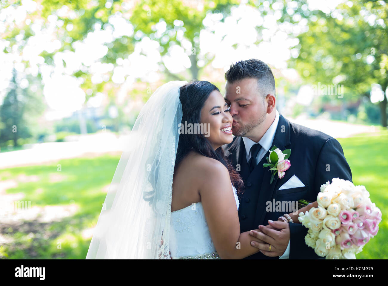 Lo sposo baci sposa moglie sulla sua guancia nel bellissimo giardino Foto Stock