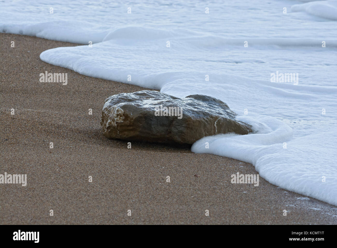 Singola pietra in surf sulla spiaggia sabbiosa, West Bay, Dorset, Regno Unito Foto Stock