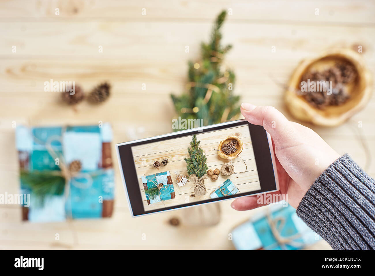 Donna di mano prendendo foto di decorazioni di Natale e regali tramite smartphone Foto Stock