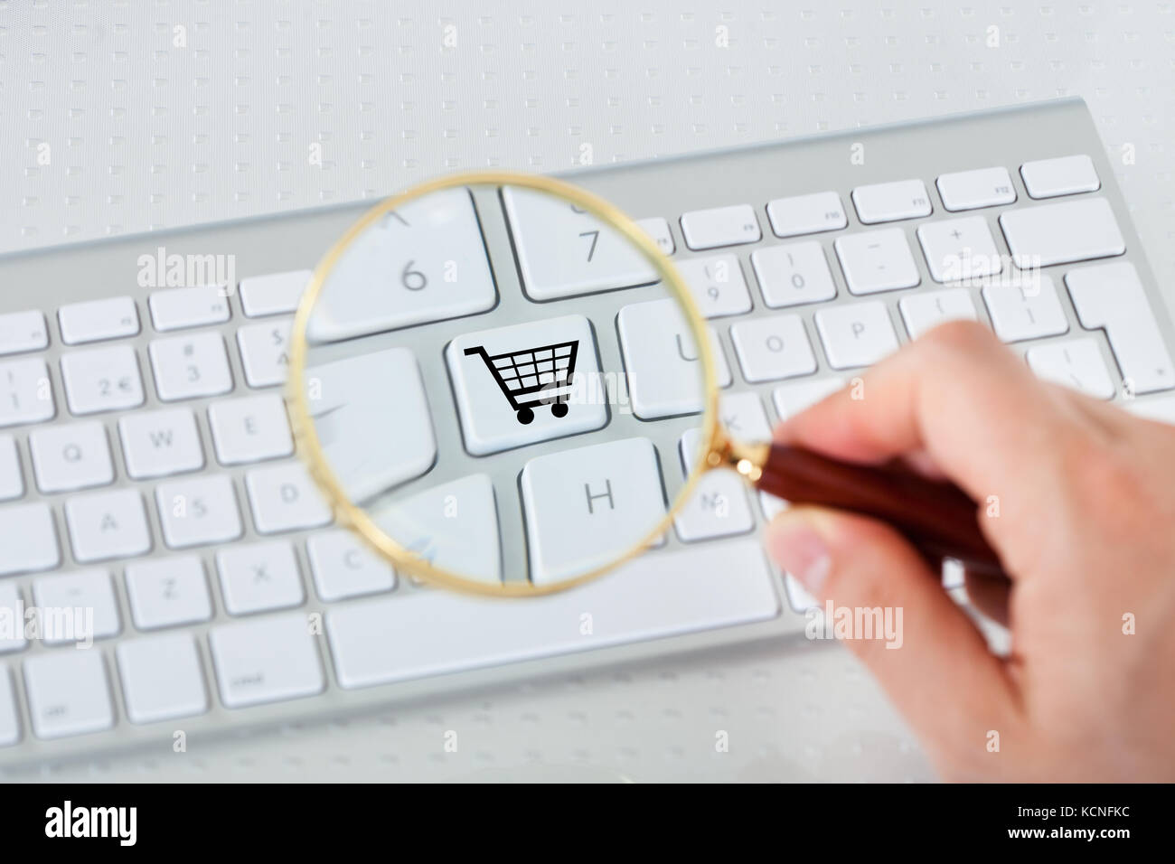 Close-up di mano guardando Shopping basket chiave attraverso la lente di ingrandimento Foto Stock