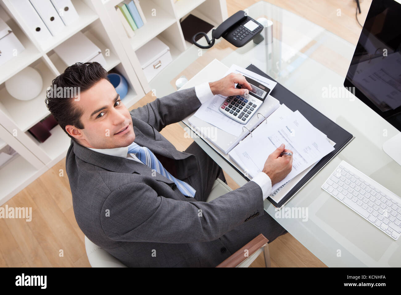 Imprenditore calcolare i documenti utilizzando la calcolatrice in office Foto Stock