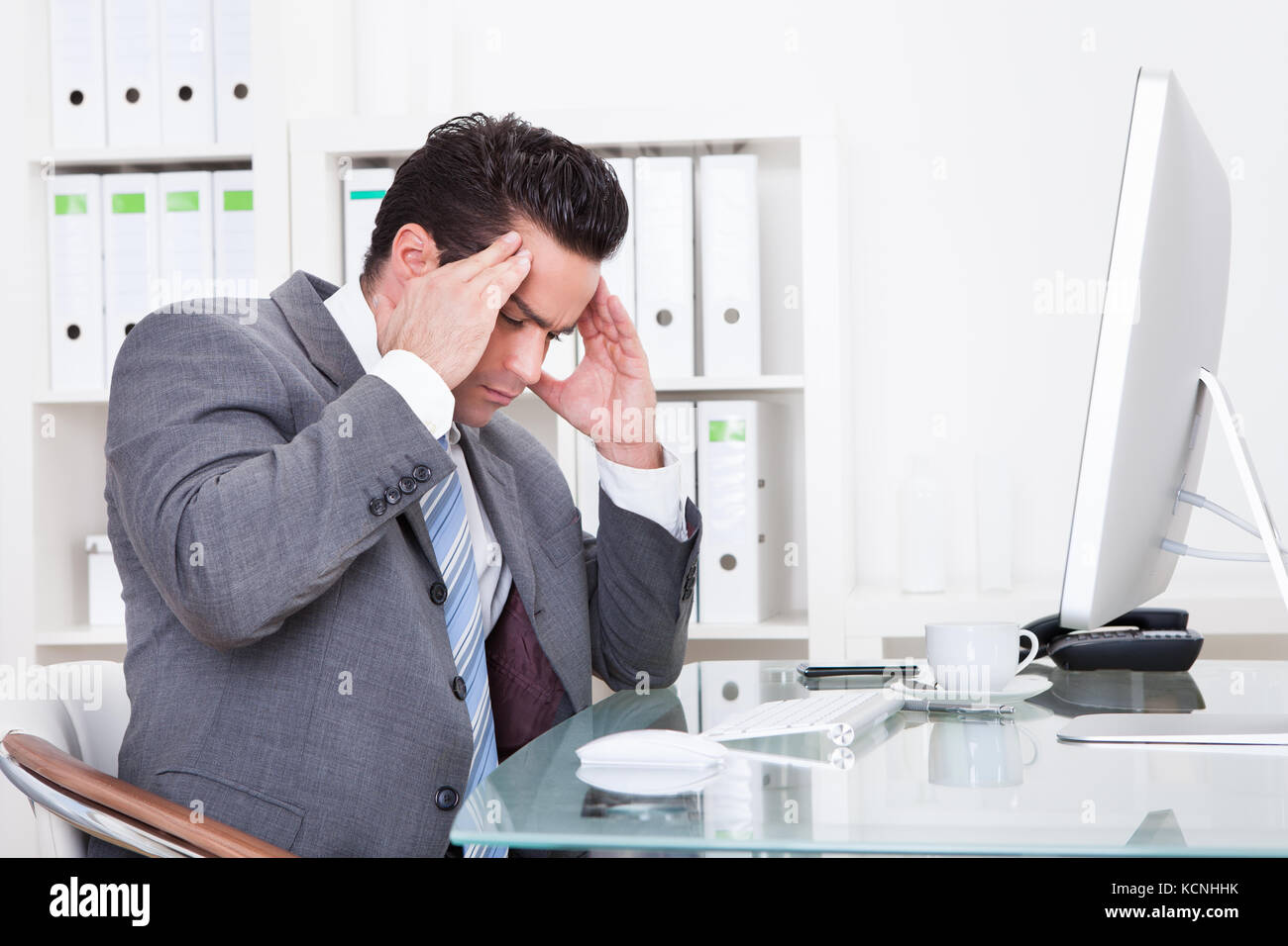 Giovane Imprenditore in ufficio presso il Desk che soffrono di mal di testa Foto Stock