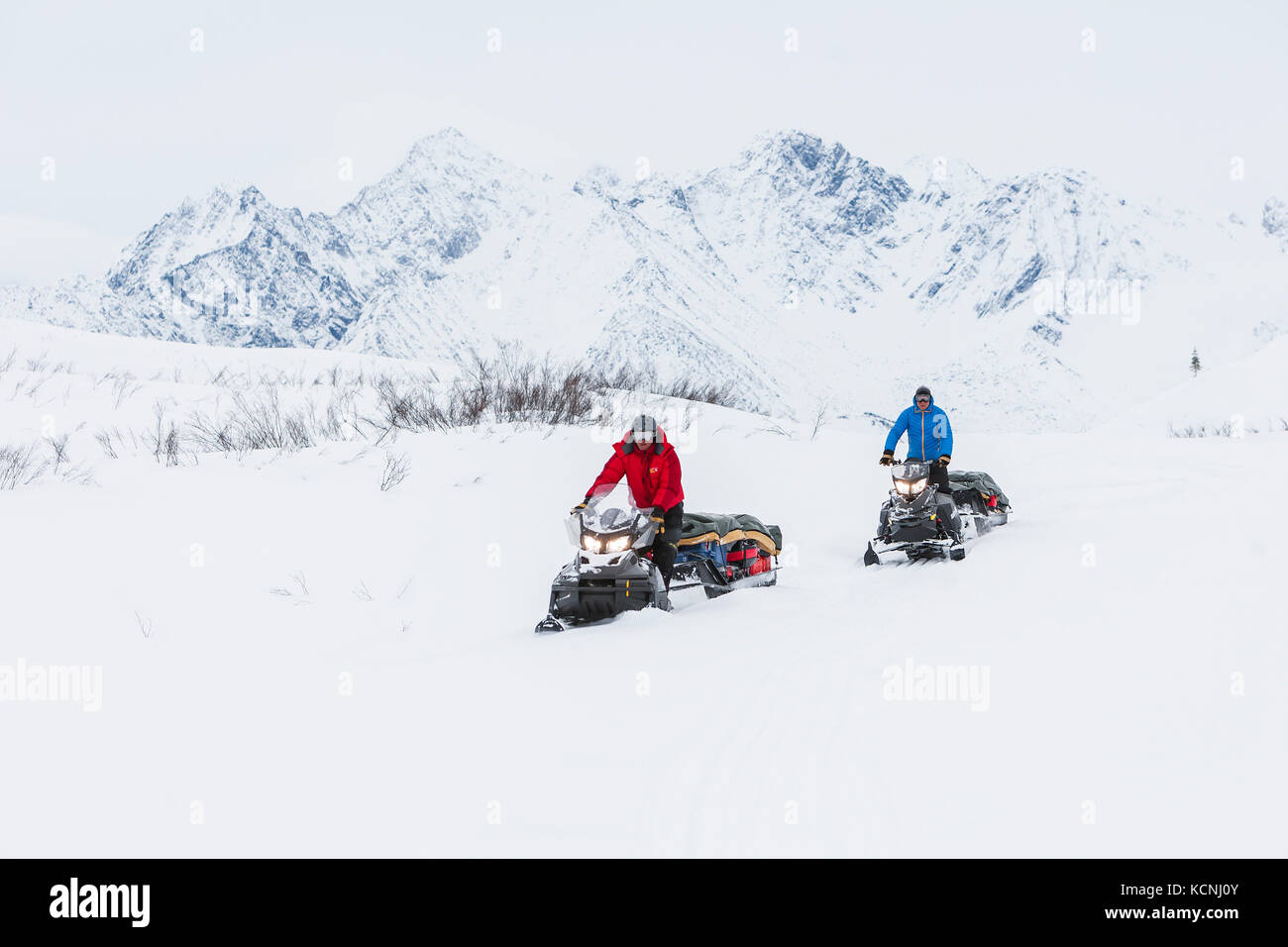 Due snowmobilier che si dirigono lungo il Canol Heritage Trail attraversano le McKenzie Mountains vicino allo Yukon e al confine nord-occidentale del territorio, il Canada settentrionale, Canada Foto Stock