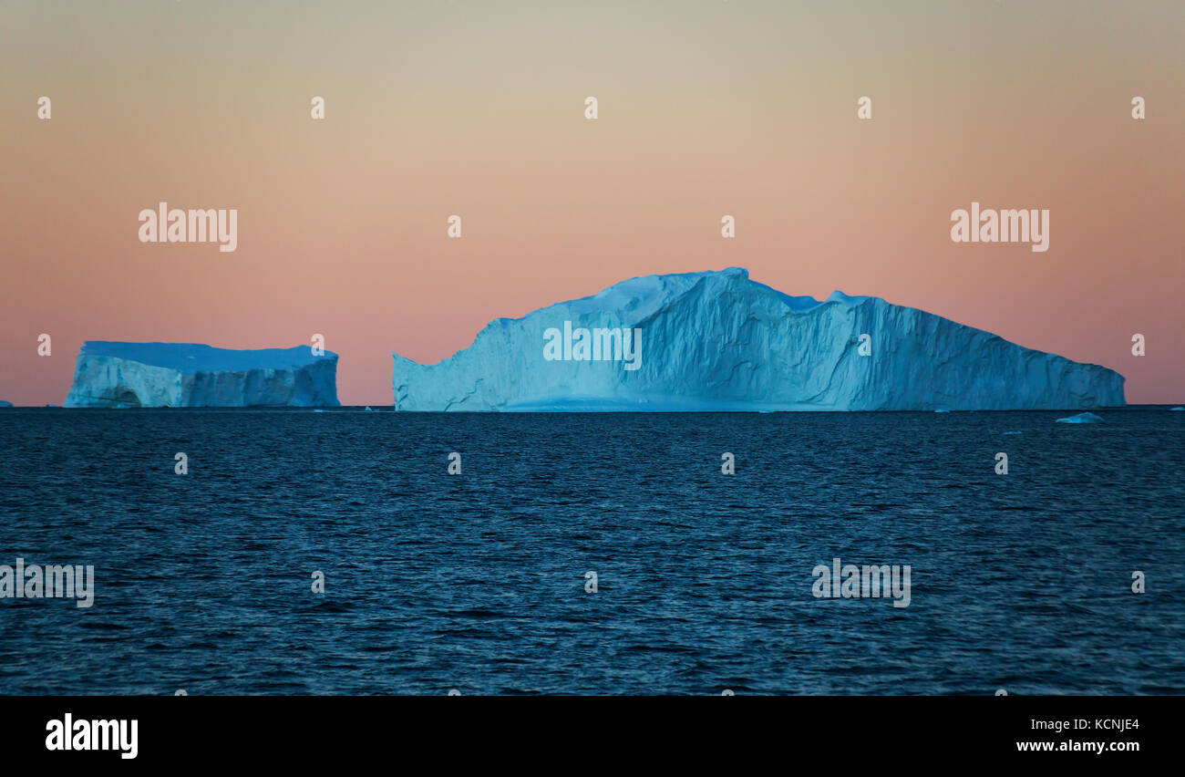 Twilight trova iceberg galleggianti in acqua contro un arancio cielo privo di nuvole vicino fournier bay, penisola antartica Foto Stock