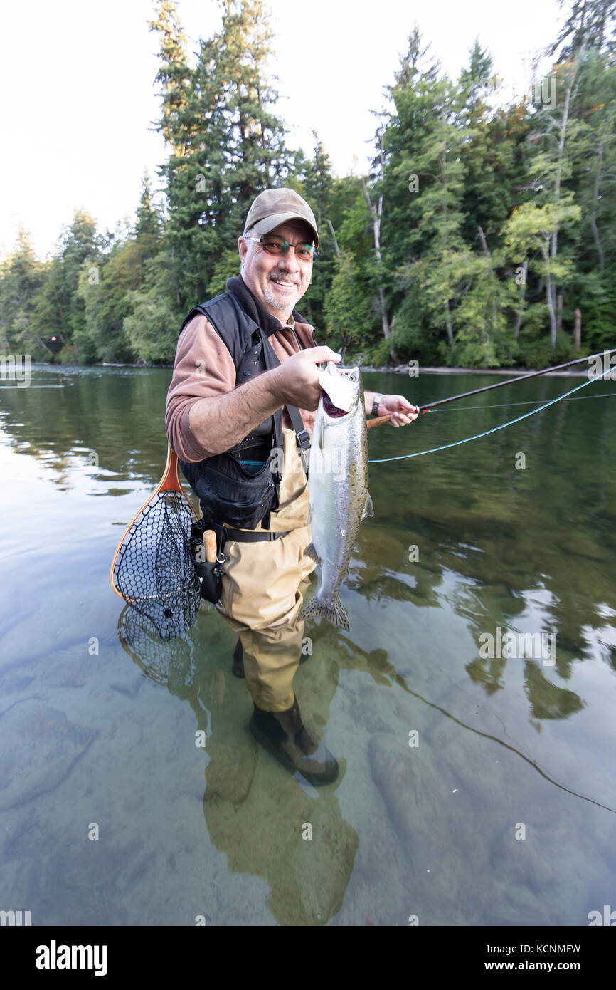 Un orgoglioso fly fisherman visualizza la sua cattura durante la pesca di fiume Campbell, isola di Vancouver. Foto Stock