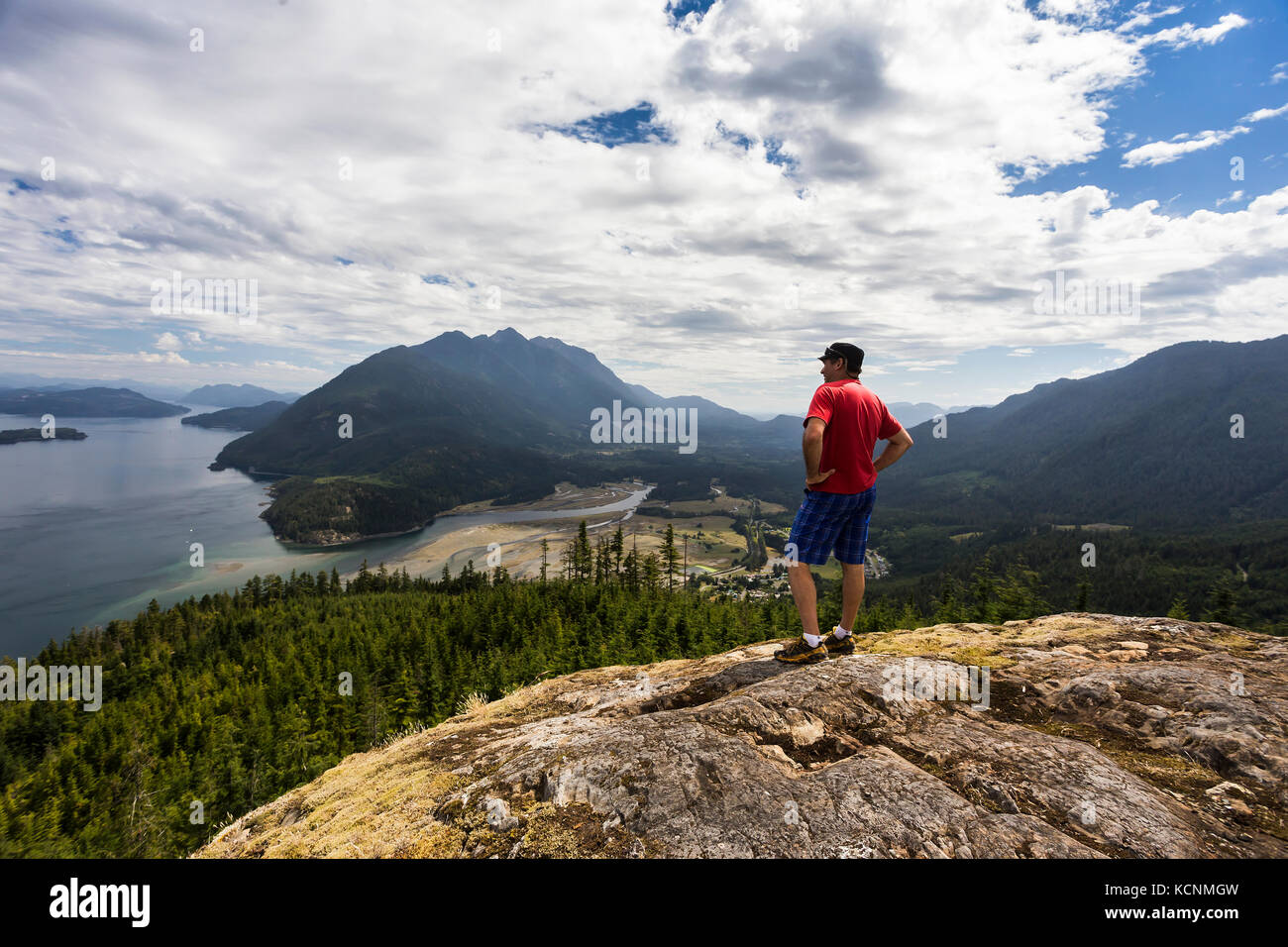 Un escursionista è ricompensato con splendide vedute della baia di Kelsey, Johnstone strait e il salmone estuario del fiume da un punto di vista di alta sopra la valle Sayward, Isola di Vancouver. Foto Stock