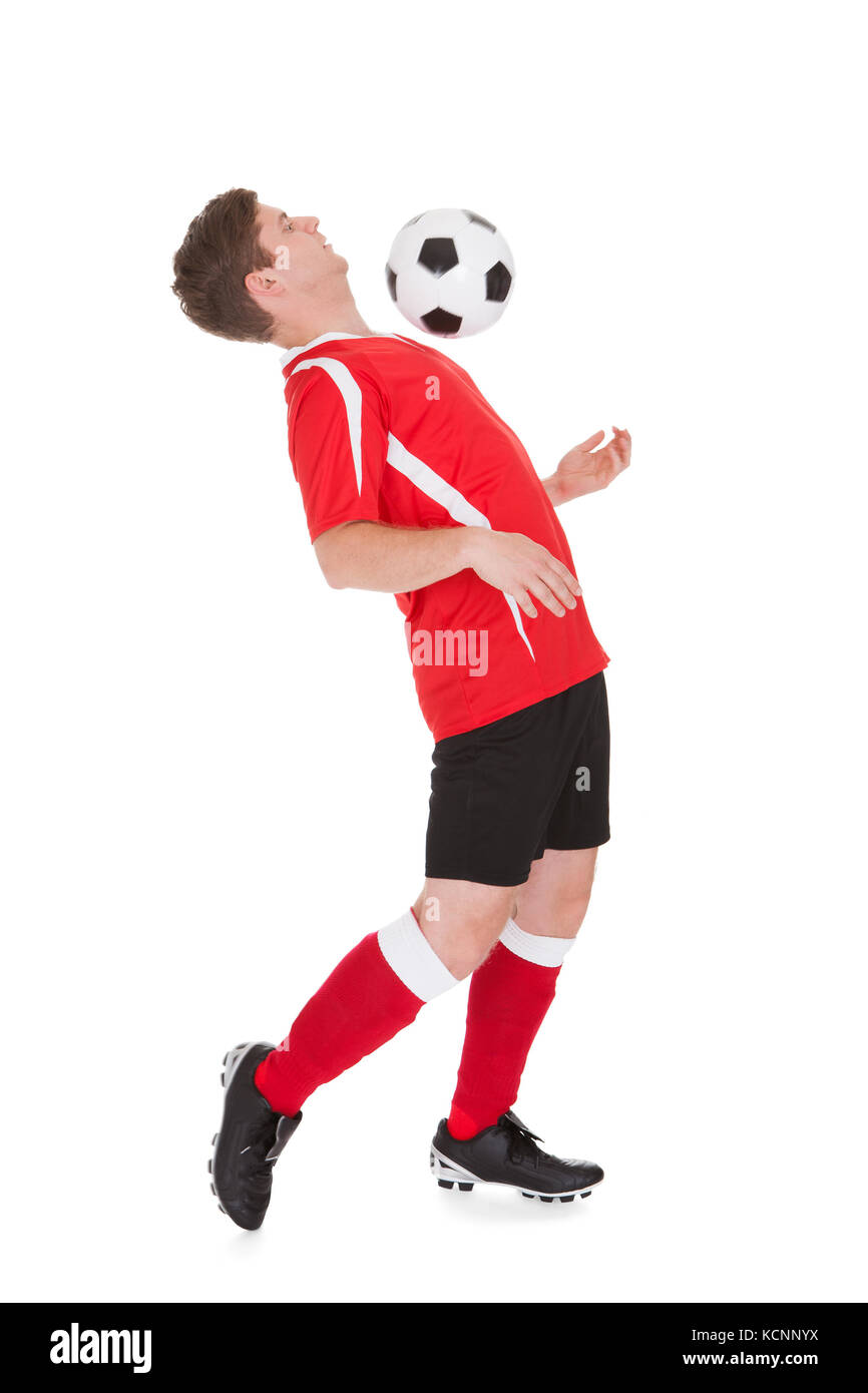 Giocatore di calcio giocando con la palla su sfondo bianco Foto Stock