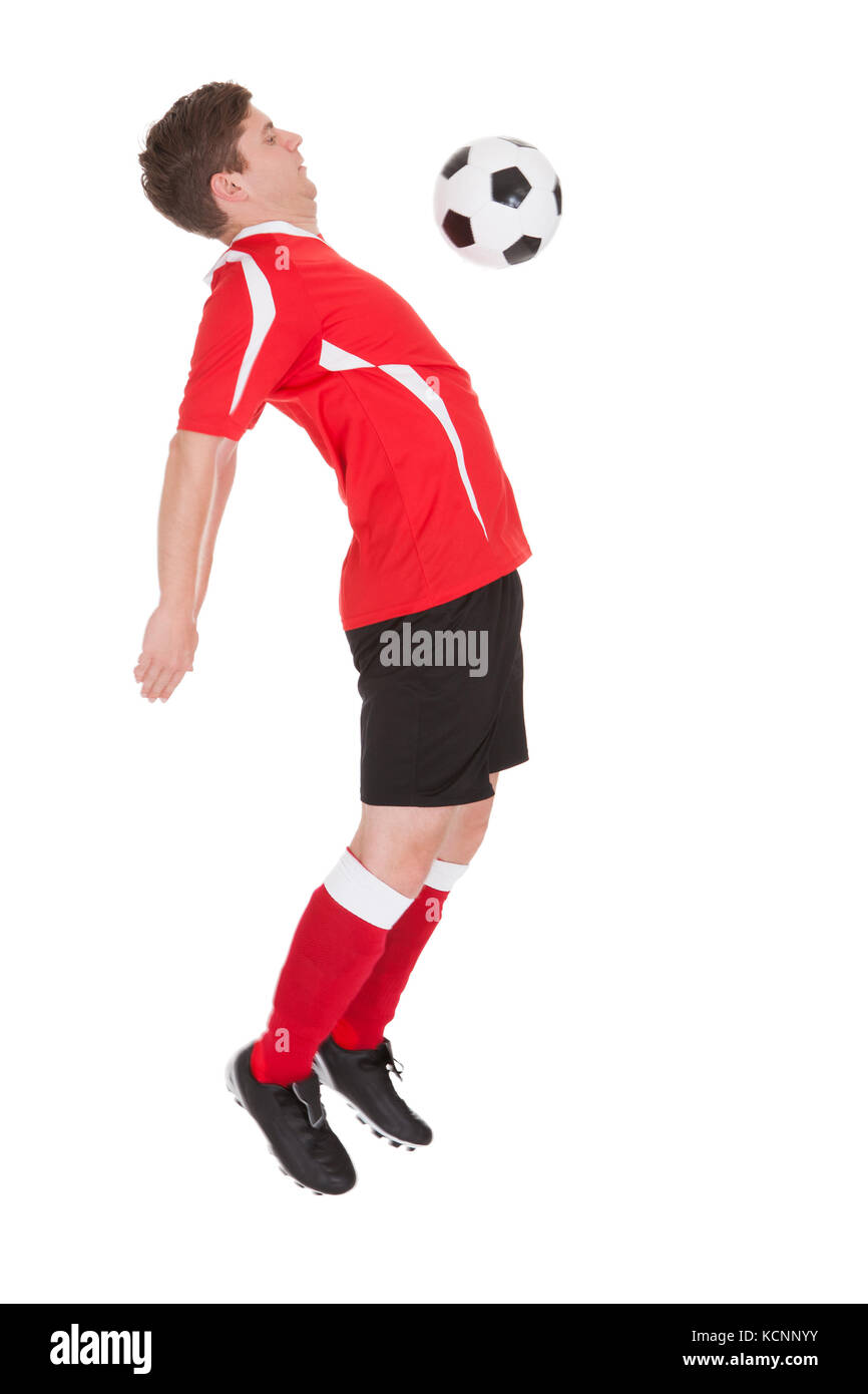 Giocatore di calcio giocando con la palla su sfondo bianco Foto Stock