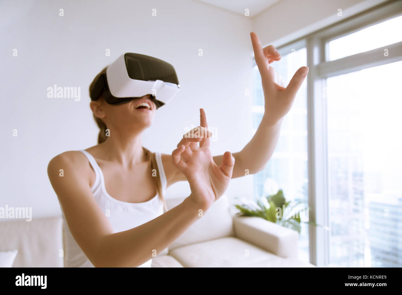 Giovani entusiasti donna che indossa le cuffie vr toccando gli oggetti in un mondo virtuale di utilizzare occhiali di applicazioni mobili innovative per l'istruzione, shopping in 3d st Foto Stock